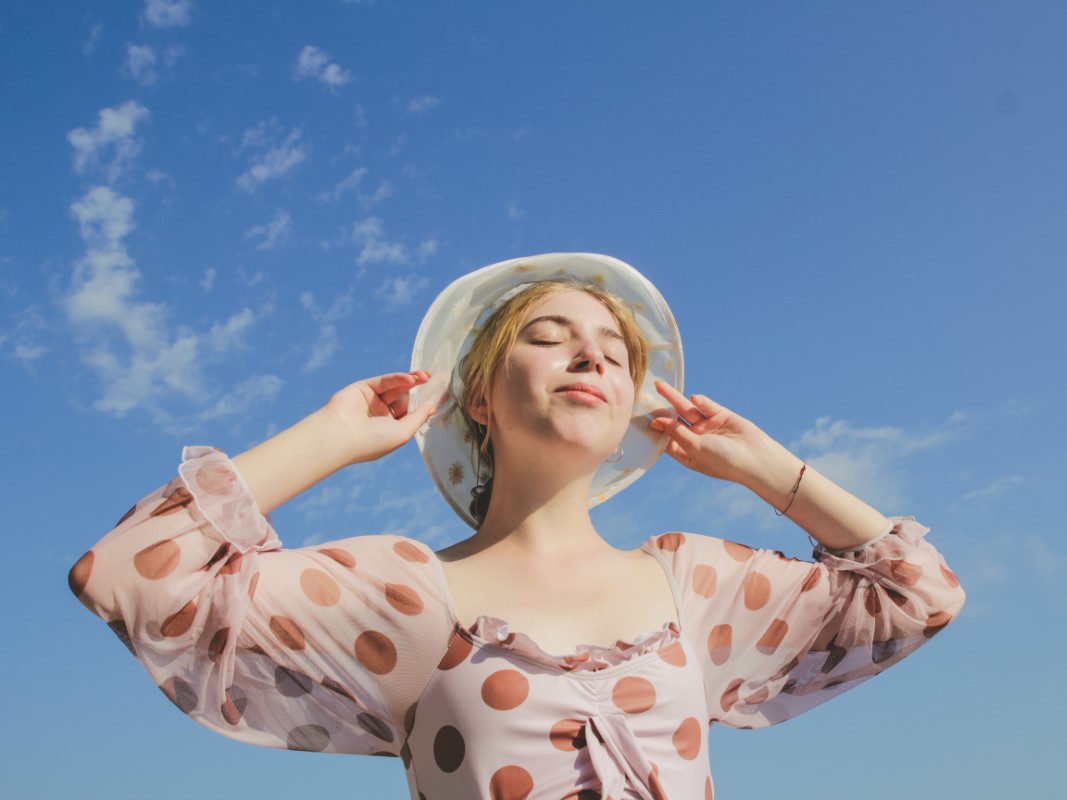 Mujer exponiendo su rostro al sol protegida para evitar manchas en la cara por sol